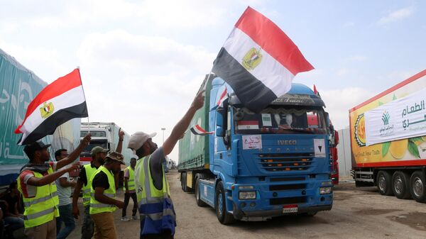 People on the Egyptian side of the Rafah border crossing wave flags as a convoy of lorries carrying humanitarian aid crosses to the Gaza Strip on October 22, 2023. - Sputnik Afrique