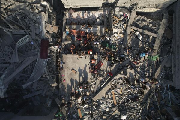 Palestinians inspect the rubble of buildings hit by an Israeli airstrike at Al Shati Refugee Camp on October 12. - Sputnik Africa