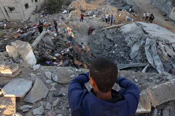 A young boy looks on as people check the rubble of a building destroyed in an Israeli bombardment in Rafah in the southern Gaza Strip on Saturday. - Sputnik Africa