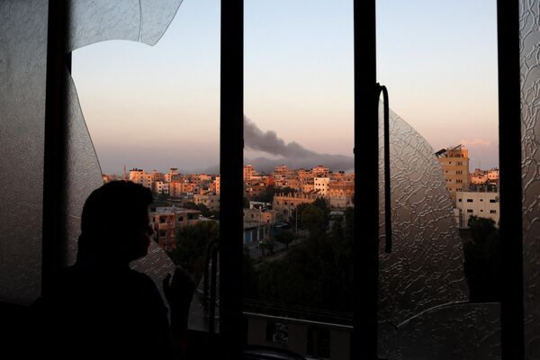A Palestinian child watches as smoke billows on the horizon after an Israeli air strike in Gaza City on October 13. - Sputnik Africa