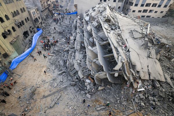 People inspect the ruins of a building destroyed by Israeli strikes in Gaza City - Sputnik Africa