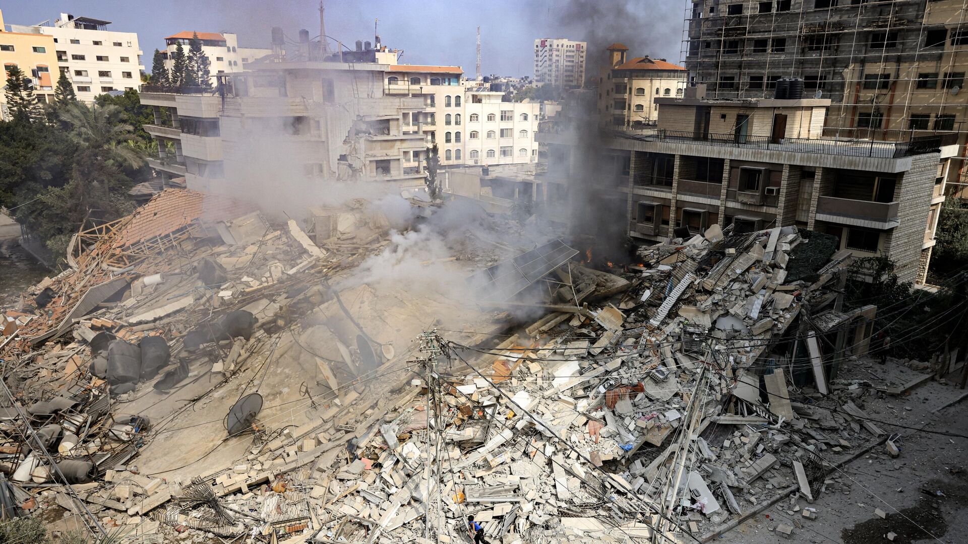 De la fumée s'élève sous les décombres d'un bâtiment détruit par une frappe aérienne israélienne dans la ville de Gaza - Sputnik Afrique, 1920, 23.10.2023