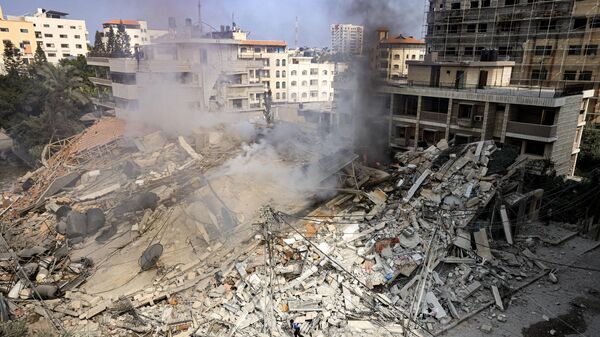 De la fumée s'élève sous les décombres d'un bâtiment détruit par une frappe aérienne israélienne dans la ville de Gaza - Sputnik Afrique