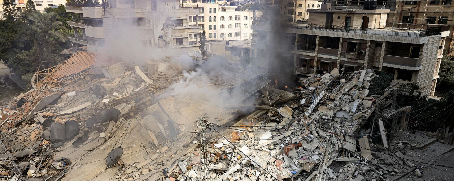 De la fumée s'élève sous les décombres d'un bâtiment détruit par une frappe aérienne israélienne dans la ville de Gaza - Sputnik Afrique, 1920, 23.10.2023