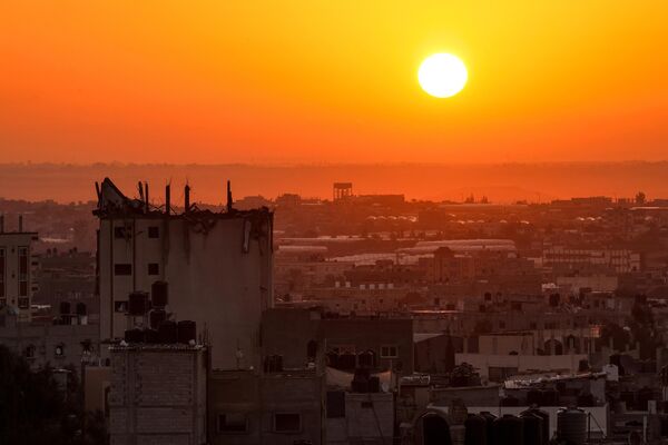 Dawn behind a destroyed building above the horizon of the city of Khan Yunis in the southern Gaza Strip - Sputnik Africa