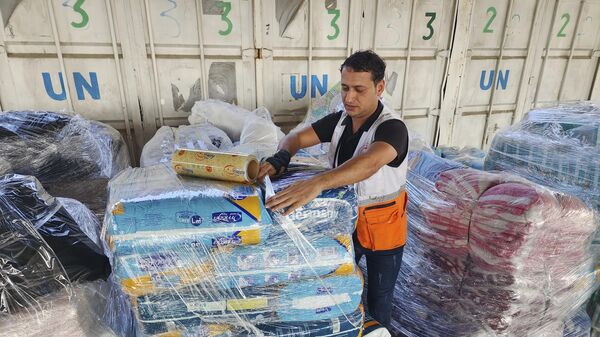 Des employés de l'Onu et du Croissant-Rouge préparent l'aide à distribuer aux Palestiniens dans un entrepôt à Deir al-Balah, dans la bande de Gaza, le 23 octobre 2023 (AP Photo/Hassan Eslaiah) - Sputnik Afrique
