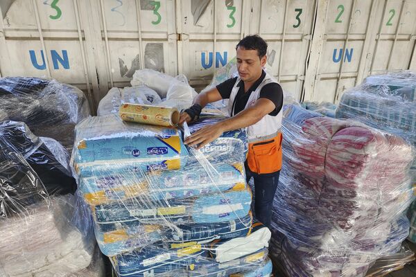 United Nations and Red Crescent workers prepare the aid for distribution to Palestinians at UNRWA warehouse in Deir Al-Balah, Gaza Strip, on Monday, Oct. 23, 2023. - Sputnik Africa