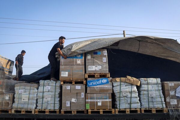 A man unloads humanitarian aid on a convoy of lorries entering the Gaza Strip from Egypt via the Rafah border crossing on October 21, 2023.  - Sputnik Africa