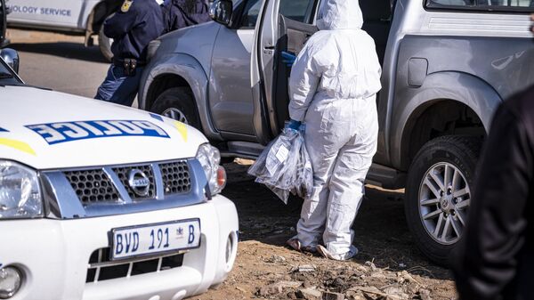 A forensic pathologist holds evidence bags from the crime scene where 14 people where shot dead in a tavern in Soweto on July 10, 2022. - Sputnik Africa