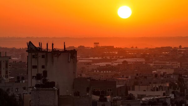 The sun rises behind a damaged building over the skyline of Khan Yunis in the southern Gaza Strip on October 19, 2023. - Sputnik Africa