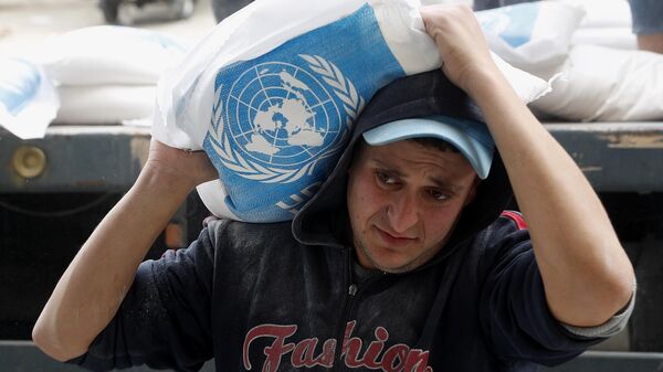 A Palestinian worker carries sacks of flour distributed by the United Nations Relief and Works Agency (UNRWA) for poor refugee families, at the Sheikh Redwan neighborhood of Gaza City, Tuesday, March 31, 2020.  - Sputnik Africa