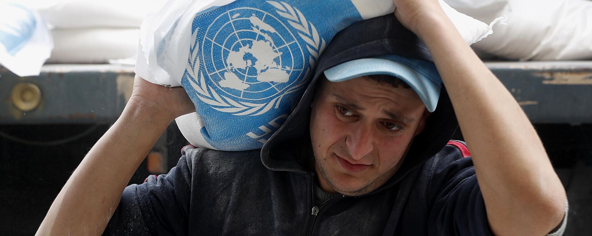 A Palestinian worker carries sacks of flour distributed by the United Nations Relief and Works Agency (UNRWA) for poor refugee families, at the Sheikh Redwan neighborhood of Gaza City, Tuesday, March 31, 2020.  - Sputnik Africa, 1920, 27.10.2023