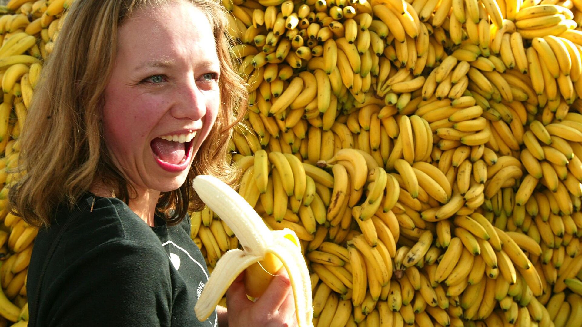 An unidentified girl eats a banana  in front of US artist Doug Fishbone's art installation, 30,000 Bananas, in London's Trafalgar Square, Tuesday Oct. 5, 2004.  - Sputnik Africa, 1920, 28.10.2023