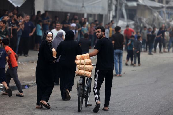 A man carries bags of food on a bicycle in the aftermath of Israeli strikes in Gaza City on October 28, 2023. - Sputnik Africa