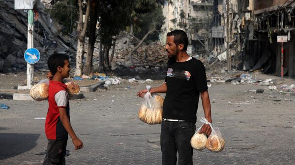 Des personnes avec du pain devant un bâtiment détruit par les frappes israéliennes sur la ville de Gaza. - Sputnik Afrique