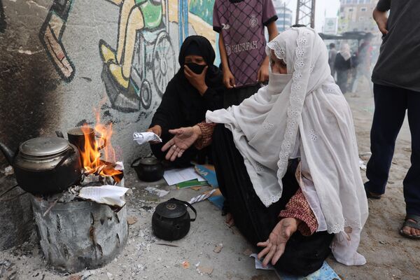 Women burn paper to heat water for tea in Rafah in the southern Gaza Strip on October 28, 2023. - Sputnik Africa