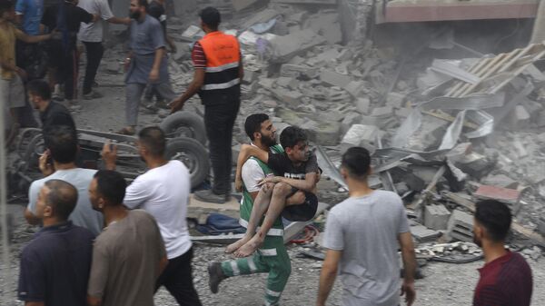 Член палестинской гражданской обороны несет раненого мальчика, спасенного из-под обломков дома семьи Таттари, который был разрушен в результате израильского авиаудара по городу Газа - Sputnik Afrique