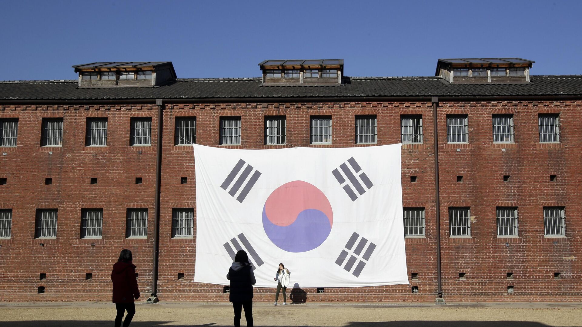 In this Friday, Nov. 29, 2013 photo, visitors take their souvenir photos in front of a huge South Korean national flag hang on the wall of the prison building at Seodaemun Prison History Hall in Seoul, South Korea.  - Sputnik Africa, 1920, 30.10.2023