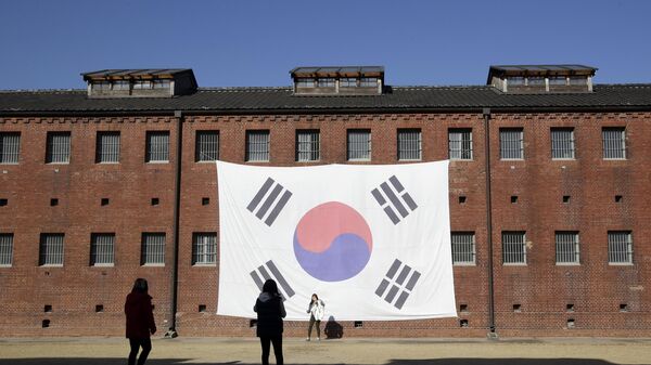 In this Friday, Nov. 29, 2013 photo, visitors take their souvenir photos in front of a huge South Korean national flag hang on the wall of the prison building at Seodaemun Prison History Hall in Seoul, South Korea.  - Sputnik Africa