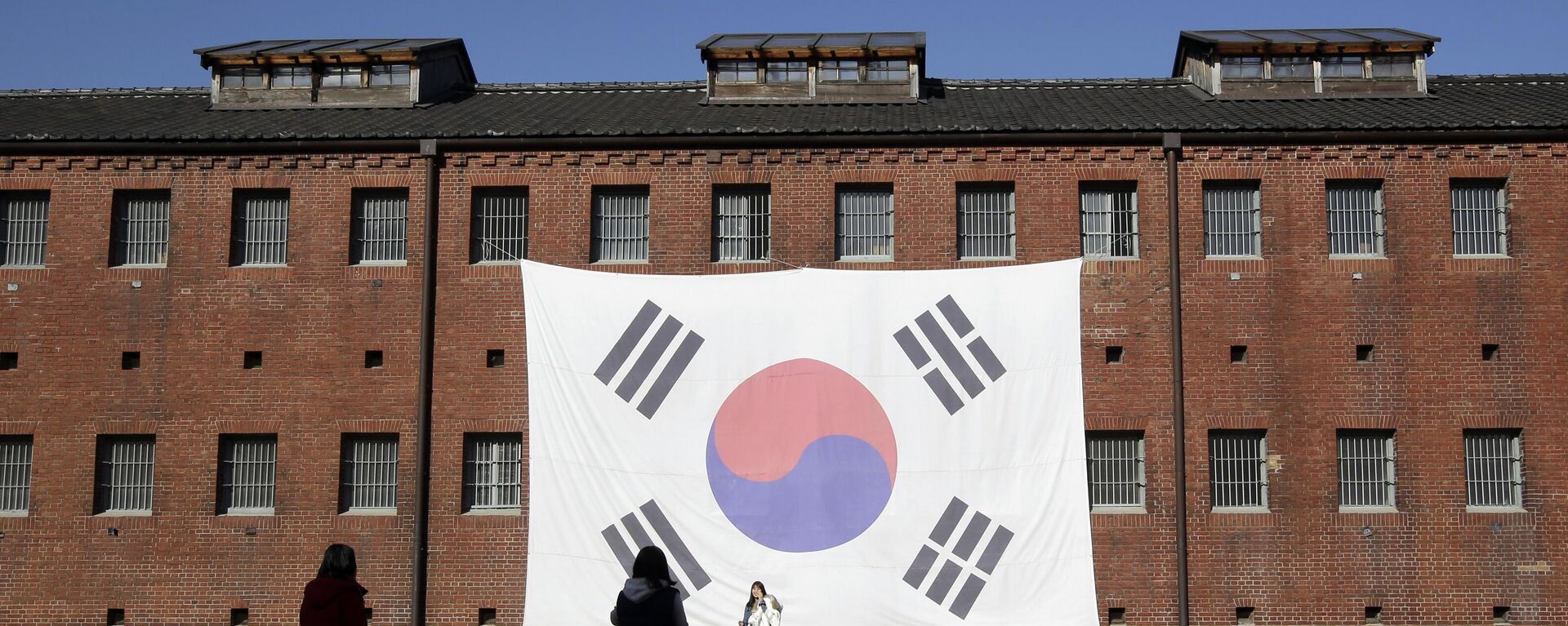 In this Friday, Nov. 29, 2013 photo, visitors take their souvenir photos in front of a huge South Korean national flag hang on the wall of the prison building at Seodaemun Prison History Hall in Seoul, South Korea.  - Sputnik Africa, 1920, 30.10.2023