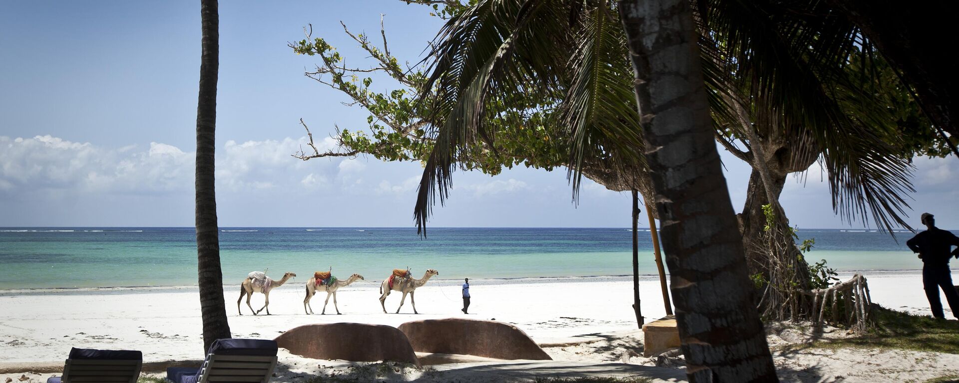 In this photo taken Wednesday, March 28, 2012, a man offering camel rides for tourists leads his animals along the Indian Ocean beach of Diani, a popular tourist destination on the coast of Kenya.  - Sputnik Africa, 1920, 30.10.2023