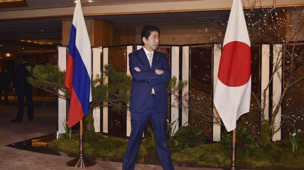 Japanese Prime Minister Shinzo Abe standing between flags of Russia, left, and Japan  - Sputnik Africa