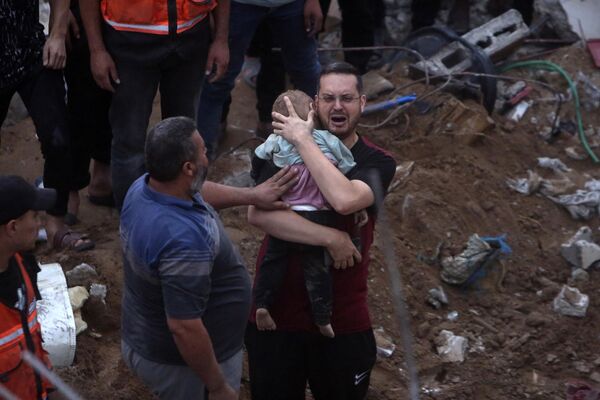 A distraught Palestinian man holding a dead child who was found under the rubble of a demolished building following Israeli airstrikes on the Nusseirat refugee camp, in the central Gaza Strip, Tuesday, Oct. 31, 2023. - Sputnik Africa