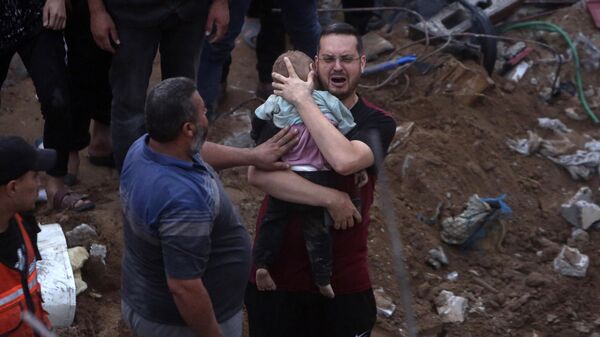 A greiving man holds a dead child after the Gaza Strip's Nusseirat refugee camp was hit by an airstrike. - Sputnik Africa
