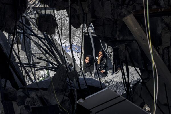 Two women peer out of a destroyed building&#x27;s window in Rafah, located in the southern Gaza Strip, looking at the destructive aftermath of Israel&#x27;s bombardment, Tuesday, Oct. 31, 2023. - Sputnik Africa