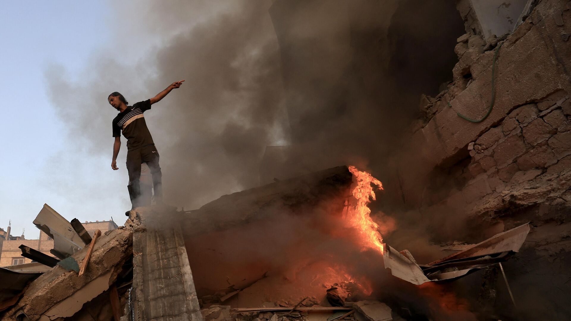 A Palestinian man gestures as he stands on the rubble of a collapsed building as a fire burns following a strike by the Israeli military on Khan Yunis in the southern Gaza Strip on November 4 , 2023, amid the ongoing battles between Israel and the Palestinian resistance movement Hamas. - Sputnik Africa, 1920, 09.11.2023