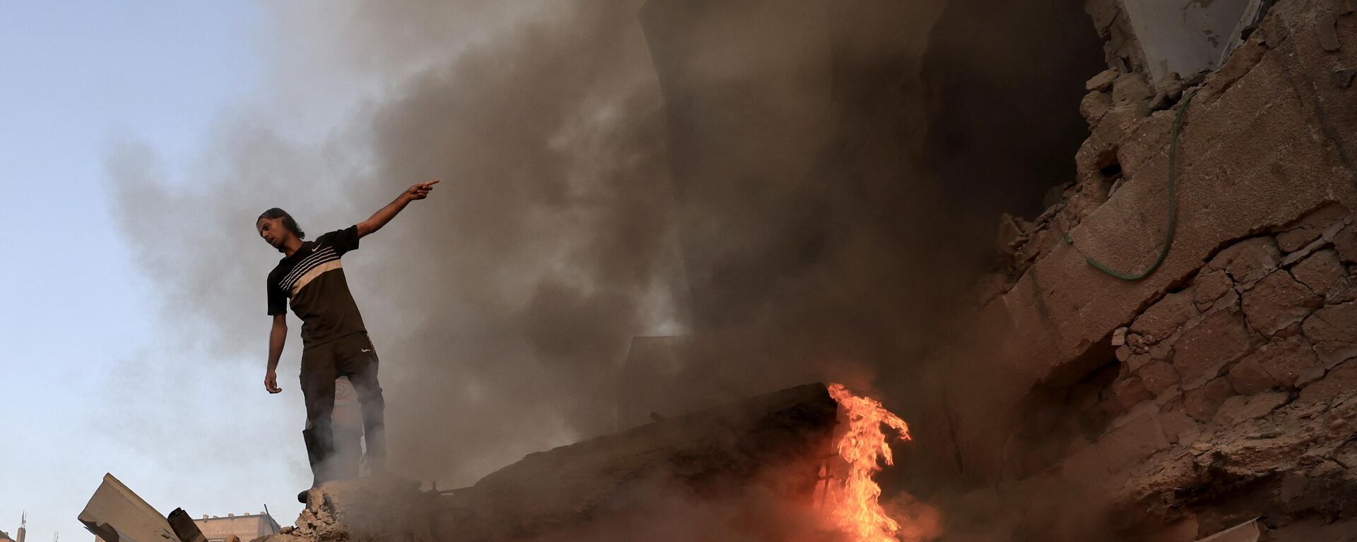 A Palestinian man gestures as he stands on the rubble of a collapsed building as a fire burns following a strike by the Israeli military on Khan Yunis in the southern Gaza Strip on November 4 , 2023, amid the ongoing battles between Israel and the Palestinian resistance movement Hamas. - Sputnik Africa, 1920, 09.11.2023