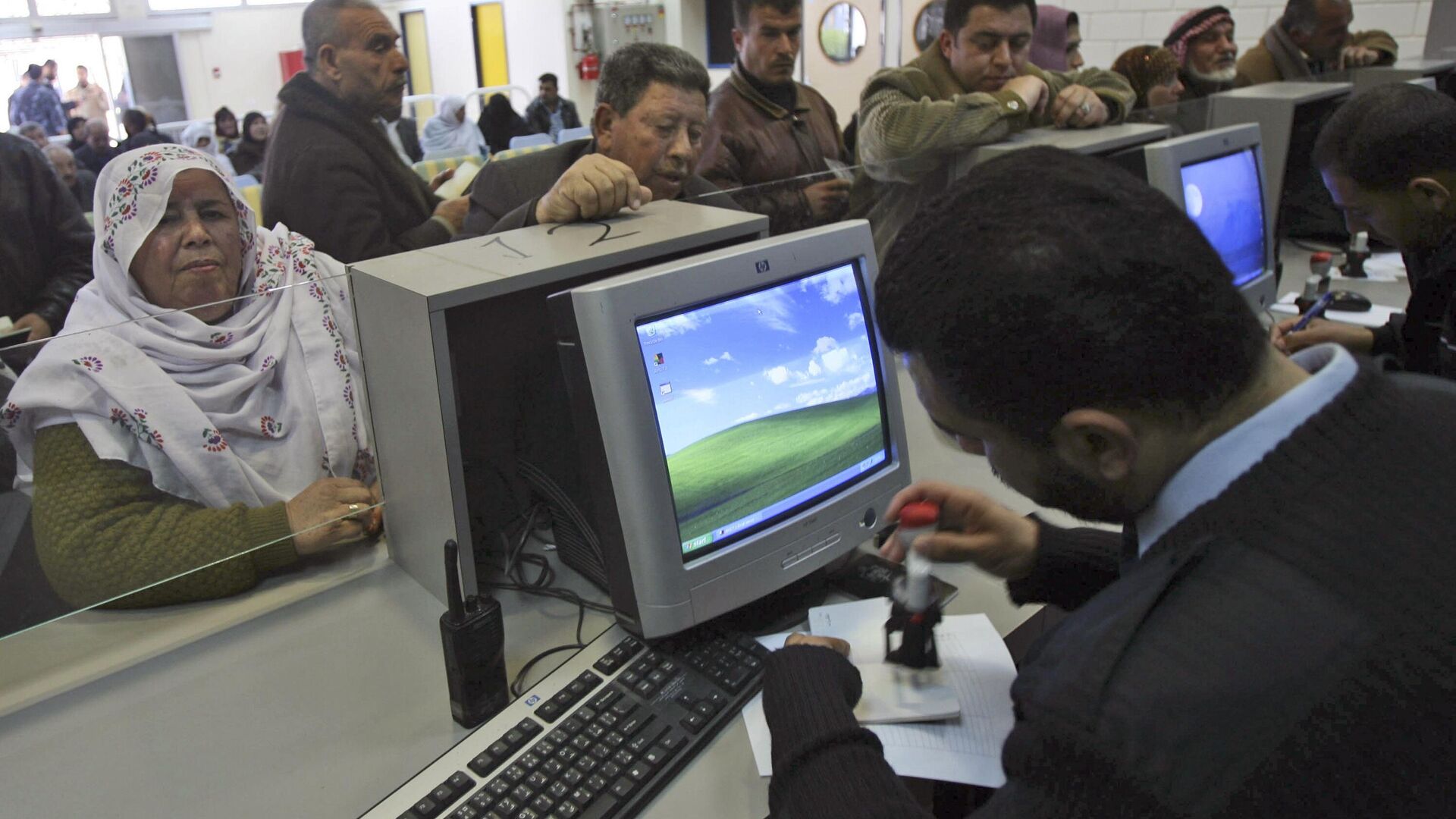 A Palestinian Hamas official stamps a passport at the passport control as Palestinians wait to cross to Egypt, at Rafah terminal in Rafah, southern Gaza Strip, Monday, Feb. 11, 2008.  - Sputnik Africa, 1920, 04.11.2023