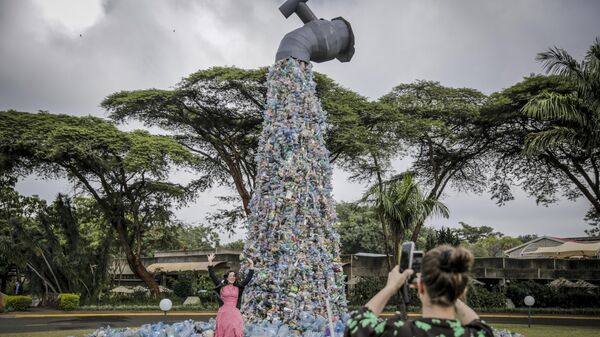 Delegates take photos of themselves in front of a giant art sculpture showing a tap outpouring plastic bottles, each of which was picked up in the neighborhood of Kibera, during the U.N. Environment Assembly (UNEA) held at the U.N. Environment Programme (UNEP) headquarters in Nairobi, Kenya Wednesday, March 2, 2022.  - Sputnik Africa
