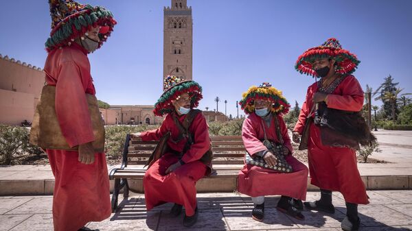 Moroccan water sellers, who have been impacted by the COVID-19 crisis since its start due to the scarcity of tourism, chat in front of the Koutoubia mosque in the city of Marrakesh, on May 6, 2021.  - Sputnik Africa