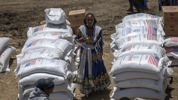 An Ethiopian woman stands by sacks of wheat to be distributed by the Relief Society of Tigray in the town of Agula, in the Tigray region of northern Ethiopia on May 8, 2021. - Sputnik Africa