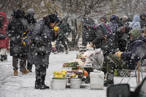 A woman chooses apples from a street vendor in snowfall in St. Petersburg, Russia, Tuesday, Nov. 21, 2023.  - Sputnik Africa