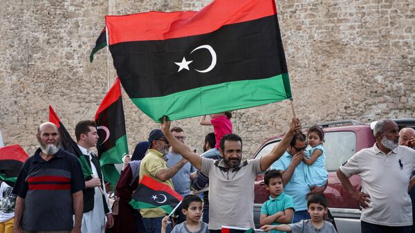 A man waves a Libyan national flag as people celebrate in the capital Tripoli on June 4, 2020, after the UN-recognised Government of National Accord (GNA) said it was back in full control of the capital and its suburbs. - Sputnik Africa