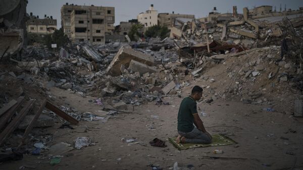 A Palestinian man prays at dusk next to rubble of his family home, destroyed by an Israeli airstrike in Beit Lahia, northern Gaza Strip, Friday, June 4, 2021.  - Sputnik Africa