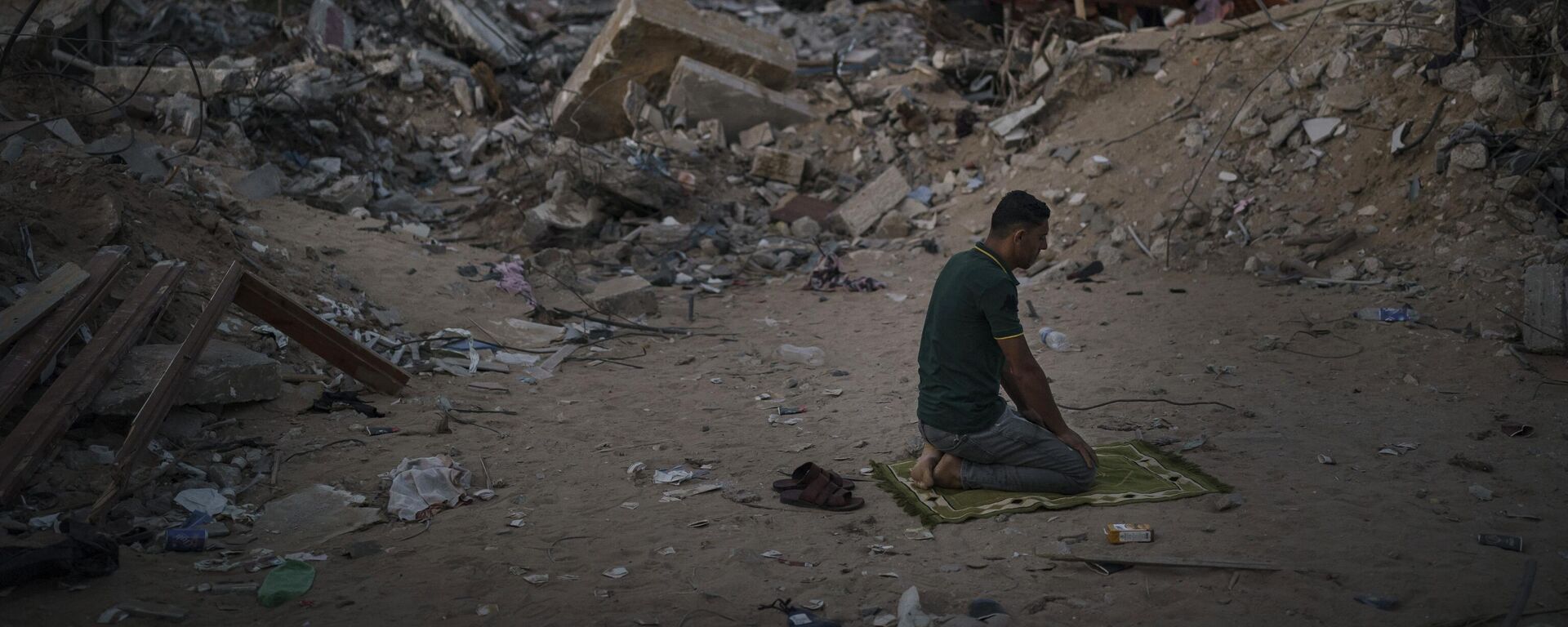 A Palestinian man prays at dusk next to rubble of his family home, destroyed by an Israeli airstrike in Beit Lahia, northern Gaza Strip, Friday, June 4, 2021.  - Sputnik Africa, 1920, 01.12.2023
