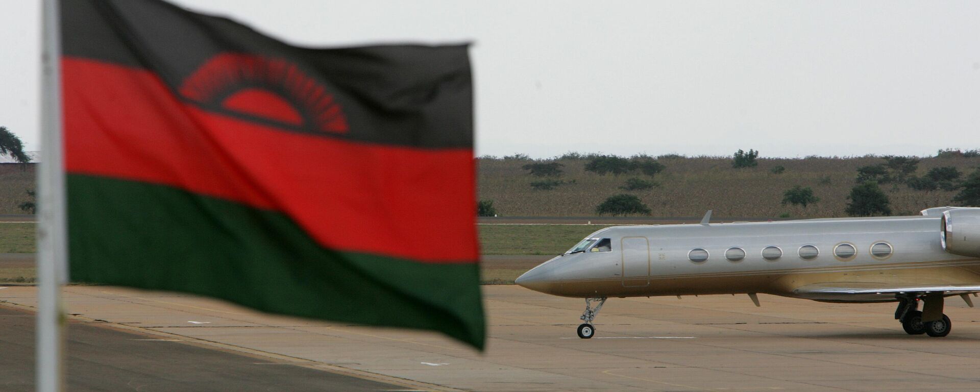 A private jet carrying U.S. singer Madonna taxis on the runway with a Malawian flag in the foreground at the Kamuzu international airport in Lilongwe, Malawi, Sunday, April 22, 2007.  - Sputnik Africa, 1920, 21.06.2024