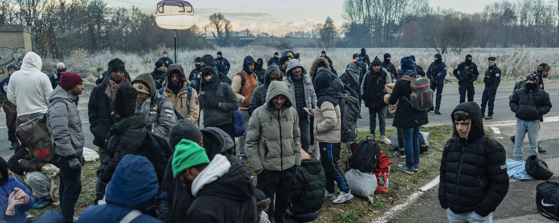 Migrants are surrounded by French National Police wait to be evacuated to reception centers during a sheltering operation by the local prefecture in Loon-Plage, northern France on November 30, 2023. - Sputnik Africa, 1920, 01.12.2023