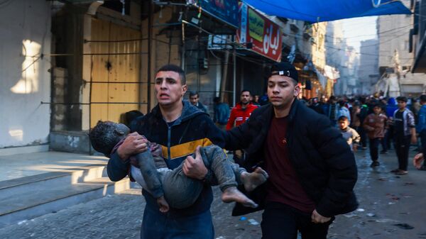 A Palestinian man carries an injured boy after the resumption of Israeli bombardment in Rafah, in the southern Gaza Strip - Sputnik Africa