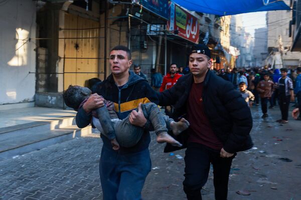 A Palestinian man carries an injured boy following the resumption of Israeli bombardment in Rafah, southern Gaza Strip, on December 1, 2023. - Sputnik Africa
