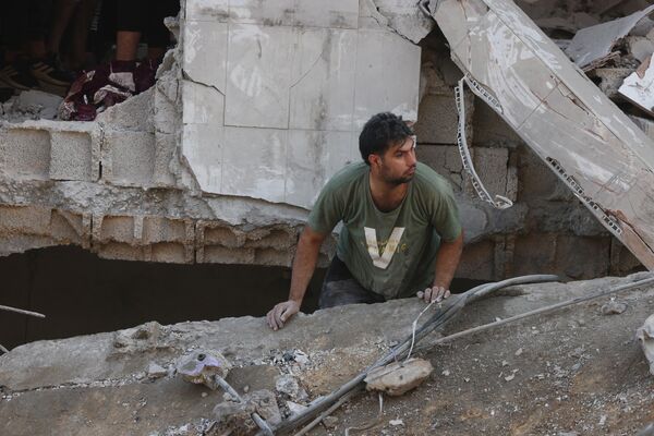 A Palestinian man looks for survivors amid the destruction in a residential building following Israeli air strikes in the Rafah refugee camp in the southern Gaza Strip on December 1, 2023. - Sputnik Africa