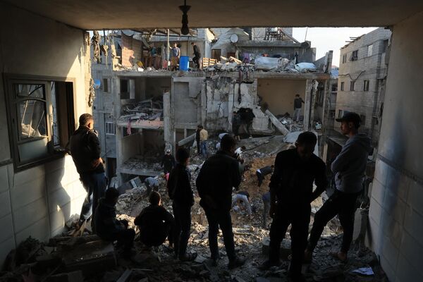 Palestinians inspect the destruction around residential buildings following Israeli air strikes in the Rafah refugee camp in the southern Gaza Strip on December 1, 2023, as fighting resumed shortly after the expiration of a seven-day truce between Israel and Hamas militants.  - Sputnik Africa