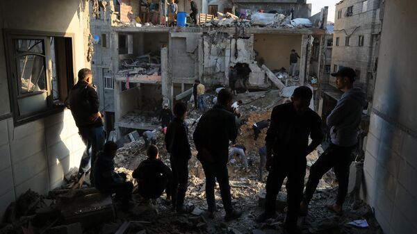 Палестинцы осматривают разрушения вокруг жилых зданий после авиаударов Израиля по лагерю беженцев Рафах  - Sputnik Africa