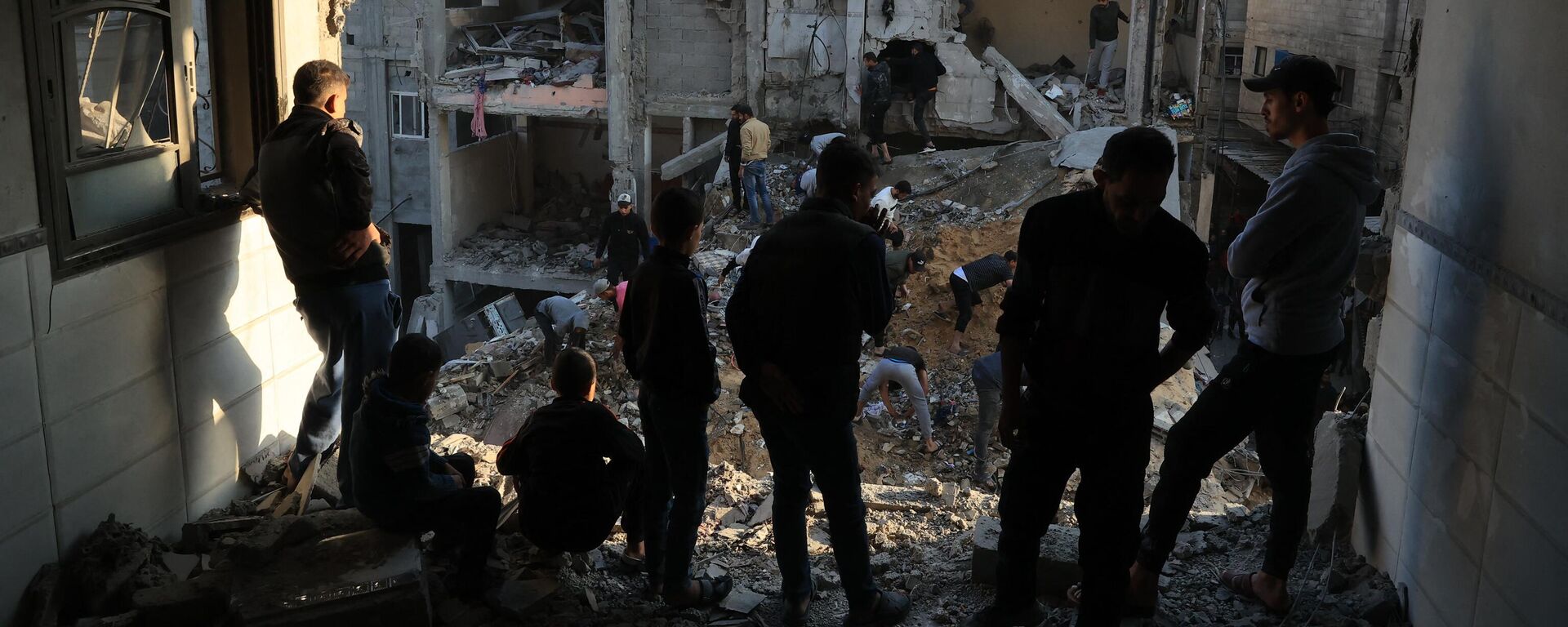 Палестинцы осматривают разрушения вокруг жилых зданий после авиаударов Израиля по лагерю беженцев Рафах  - Sputnik Africa, 1920, 03.12.2023