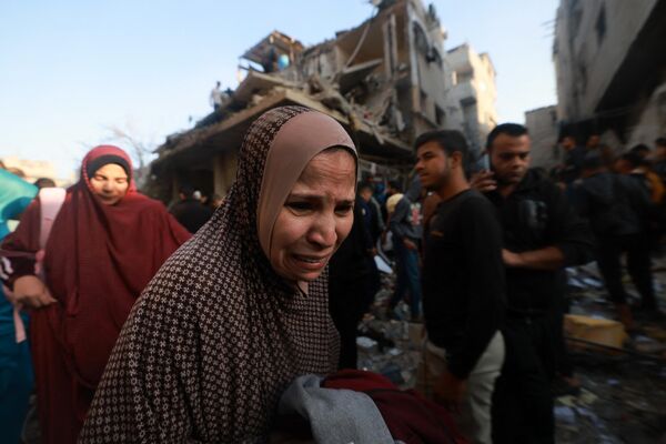 A Palestinian woman reacts as people check the rubble of a building destroyed in an Israeli air strikes on the Rafah refugee camp in the southern Gaza Strip on December 1, 2023. - Sputnik Africa