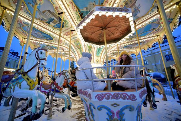 Visitors ride on a carousel on the opening day of the skating rink at Nikolsky Rows in St. Petersburg. - Sputnik Africa