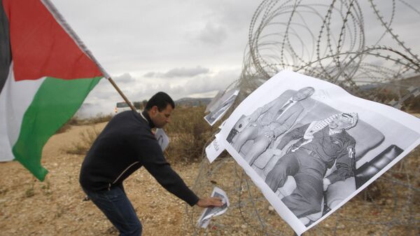 A Palestinian demonstrator places portraits of late South African Leader Nelson Mandela alongside late Palestinian leader Yasser Arafat a the wire fence during the weekly demonstration against Israel's separation barrier in the West Bank village of Bilin, near Ramallah, Friday, Dec. 6, 2013. - Sputnik Africa